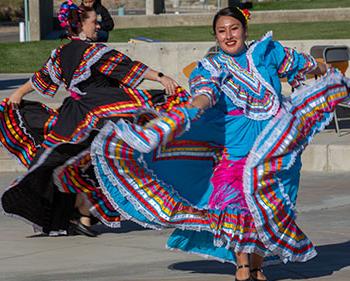 Two female dancers dressed in traditional Latina clothing dancing at outdoor event